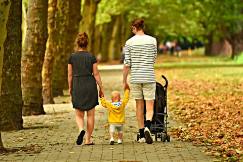 Two adults and one child walking on a street.