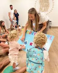 Woman showing toddlers a board.