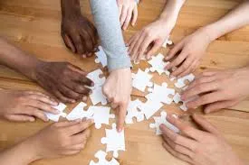 Hands working to put together a puzzle.