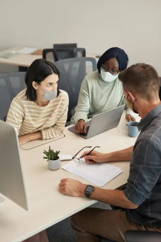 three people sitting at a table reviewing paperwork
