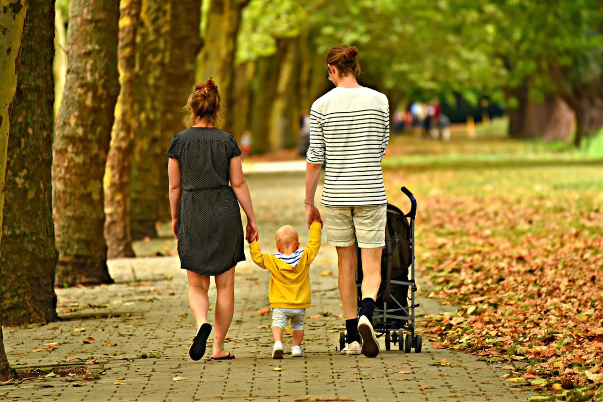 Two adults and one child walking on a street.